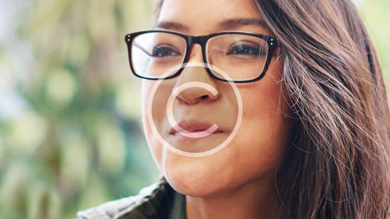 A woman wearing glasses is smiling at the camera.
