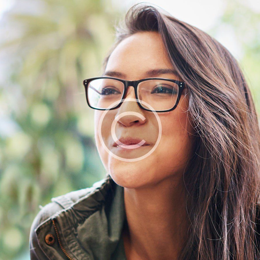 A woman wearing glasses is smiling at the camera.