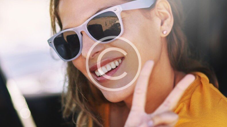 A woman wearing sunglasses and making a peace sign in a car.