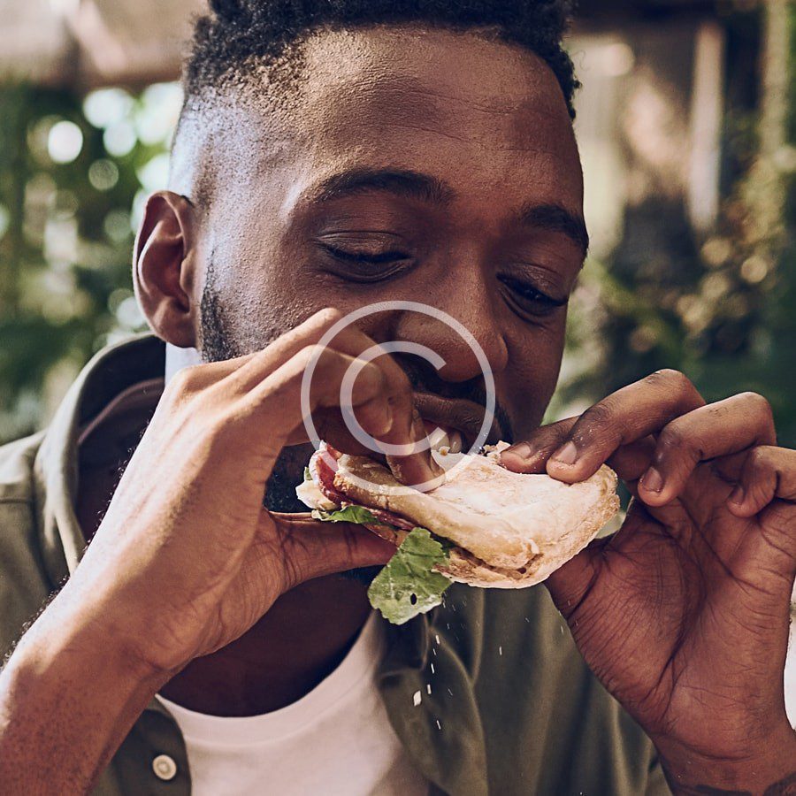 A man eating a sandwich outdoors.