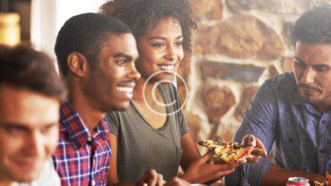A group of people eating pizza at a restaurant.