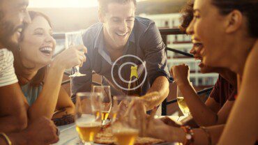 A group of people laughing at a table with wine glasses.