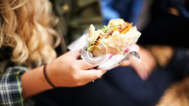 A woman is holding a burrito in her hands.