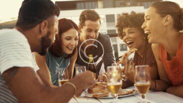 A group of people eating pizza at an outdoor table.