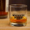 A WRS Rocks Glass on a table next to a bottle of whiskey.